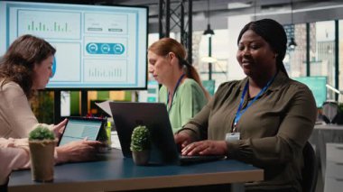 Siyahi iş kadını toplantı masasında oturuyor ve görevleri çözüyor. Ekibiyle yaptığı brifingde rapor yazıyor. Başarılı bir proje planlamak için analitik ve göstergeleri kullanmak. Kamera A.