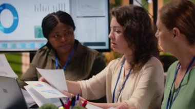 Gelişmiş bir kurumsal kültürde grafik ve strateji raporlarını değerlendiren güçlü iş kadınları, şirket gelişimine ve başarıya odaklanarak birlikte akıllıca kararlar veriyorlar. Kamera B.