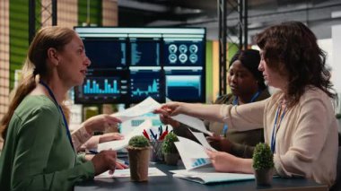 Çeşitli iş kadınları ekibi, proje hedefleri belirlemek için strateji raporlarını ve performans verilerini gözden geçirmek üzere kurumsal ofiste masanın etrafında toplanıyor. Ortaklık ve güçlenme. Kamera A.