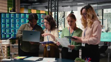 Hırslı ve hedefe yönelik çeşitli iş kadınları kurumsal raporları ve grafikleri gözden geçiriyorlar, modern bir çalışma ortamında profesyonel büyüme sağlamak için sinerji alanında çalışıyorlar. Kamera A.