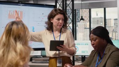 Geliştirme hedefleri olan bir proje planlayan yetkili iş ortakları, çok uluslu şirket büyümesine ilişkin veri içgörüleri ve performans göstergelerini gözden geçirmek üzere bir toplantı odasında bir araya geliyorlar. Kamera B.