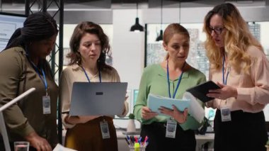 İş kadınları planlama, analiz ve tahminler üzerinde çalışmak üzere belge ve dizüstü bilgisayarların etrafında birleşik bir takım olarak toplanıyorlar. Sonuçlara ve şirket liderliğine odaklanan ortaklar. Kamera B.