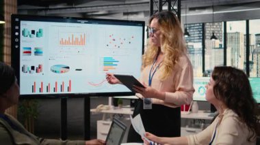 Şirketin gelişimi için veri raporlarını tartışmak ve analiz etmek üzere toplantı odasında personeline performans göstergeleri sunan hırslı bir CEO. Brifingdeki güçlü kadınlar. Kamera A.