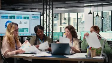 Çeşitli kadın gruplarının yeni bir strateji için biraraya gelmesi ve bilgi alışverişinde bulunması, ofisteki belgelerdeki çizelgeleri gözden geçirmesi. Hedefe yönelik güçlendirilmiş ortam, kurumsal feminizm. Kamera A.