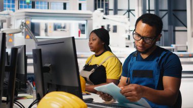 Afrika kökenli Amerikalı mühendis, bir güneş paneli imalat fabrikasında çalışarak, masaüstündeki güneş enerjisi makinelerinden veri topluyor. Otomatik yenilenebilir enerji üretim hattında erkek teknisyen. Kamera B.