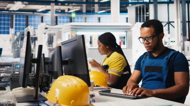 Afrika kökenli Amerikalı endüstriyel teknisyen güneş enerjisi tesislerindeki sistem sağlığını üretim işlemleri için yazılım araçları kullanarak değerlendiriyor. İşçi yeşil enerji için fotovoltaik ekipman üretiyor. Kamera B.