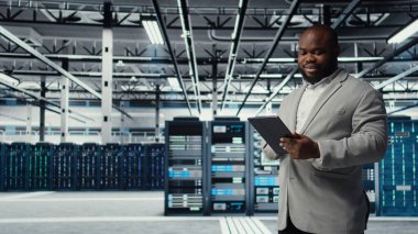 Tablet üzerinde çalışan kod hata ayıklama araçlarına bakan neşeli veri merkezi programcısı. Aygıt dokunmatik ekranında yazan, betik otomatik görevleri yazan sunucu çiftliği bilişim uzmanı, kamera A