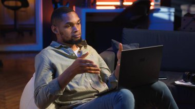 Siyahi adam internet dersine ev ortamından yeni beceriler geliştirmek için katılıyor, web konferansına katılıyor ve tavan arasından konferans seyrediyor. Sanal eğitim sınıfına katılan biri. Kamera B.