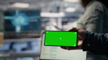 Sunucu merkezi programcısını güncellemelerin kurulumunu beklerken model telefon kullanarak kapat. Veri merkezi uzmanı, kodların derlemeyi bitirmesi için krom tuşlu akıllı telefon kullanır