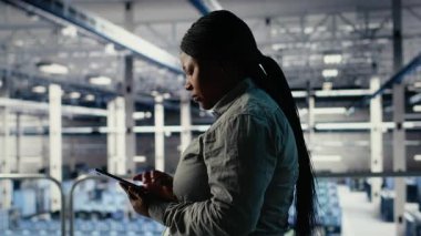 IT uzmanı endüstriyel platformda yürürken tablet kullanarak sunucuların tarım faaliyetlerini izliyor. Veri Merkezi Sistem Yöneticisi, sistemlerin doğru çalıştığından emin olmak için testlerin sonuçlarını gözden geçirir. Kamera B