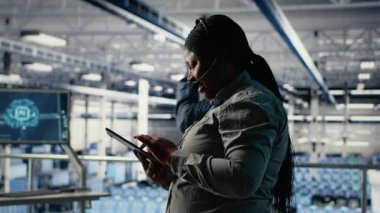 Sunucu merkezi teknik destek uzmanı şirket müşterilerine güvenli veri yedekleri kurma konusunda rehberlik ediyor. Veri merkezindeki Afrikalı Amerikalı kadın kullanıcıların sunuculardaki sistem hatalarını düzeltmelerine yardım ediyor, kamera B