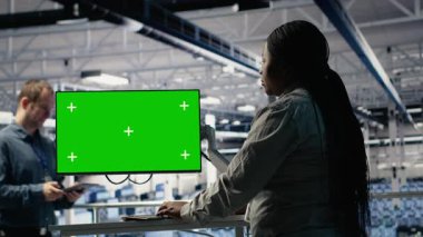 Sunucu merkezindeki yazılım geliştiricisi sorun var mı diye krom anahtar çalışma istasyonunu kullanıyor. Veri merkezindeki Afrikalı Amerikalı kadın, B kamerasında yedekleme yapmak için izole ekran bilgisayarı kullanıyor.