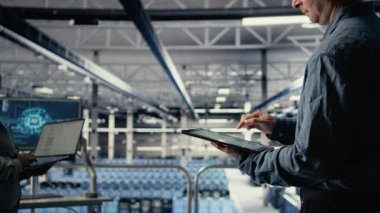 Sunucu odası çalışanı sistem sağlığını izlemek için tabletteki veri tabletlerini kontrol ediyor. Sistem yöneticisi veri merkezinin iş hedefleri ve müşteri ihtiyaçları olan kamera A 'yı karşıladığından emin olmak için grafikleri gözden geçirir