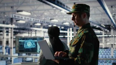 Sunucu odasındaki askeri asker ve mühendis bilgisayar sistemlerini yönetmek için yapay zeka araçları kullanıyor. Ordu komutanı ve kadın programcı sunucu çiftliğindeki yapay zeka kullanılarak incelenen bilgiler, kamera B