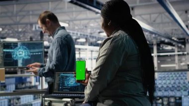 Veri merkezi yönetimi makine öğrenme teknolojisini kullanırken izole ekran akıllı telefonu kullanıyor. Sunucu odası bilişim uzmanı, veritabanlarıyla yapay zeka sistemleri eğitilirken krom anahtar telefon kullanıyor