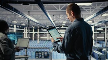 Sunucu odası bilişim uzmanı veri grafiklerini okumak ve ekipman sağlığını izlemek için tablet dokunmatik ekranından araklıyor. Yönetim, veri merkezinin hedeflere ulaştığından emin olmak için aygıt üzerindeki analiz ölçüm grafiklerini inceler, kamera A