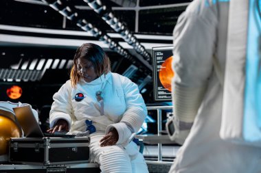 Dişi astronot, dizüstü bilgisayar kullanarak uzay aracı donanım sistemlerinde sorun çıkarıyor. Uzay gemisindeki kadın, gezegensel keşif uçuşu sırasında not defterindeki görev kayıtlarını analiz ediyor.