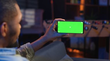 Black Freelancer oturma odasında çalışmak için tablet üzerinde yeşil ekran modelini kullanıyor, evde oturup aletleri çözüyor. Moda dünyasında rahat, genç bir yetişkin. Kamera B.