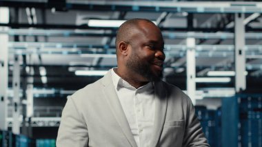 Yüksek teknoloji veri merkezi tesisinde çeşitli işlevsel sunucu raflarıyla yürüyen bir yönetici. Dijital depolama sistemleri için kurulmuş sunucu merkezini denetleyen denetleyici, kamera B