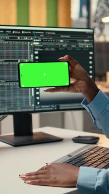 Ofisteki dikey video prop firması stajyeri yeşil ekran cep telefonundaki video dersinden yeni ticaret stratejileri öğreniyor. Komisyoncu şirket stajyeri eğitim amaçlı krom tuşlu akıllı telefon kullanıyor.