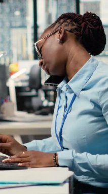 Ofisteki dikey video Equity analisti üç aylık kazanç belgelerini inceleyip gelecekteki borsa değerini belirliyor, telefonda konuşuyor. Tüccarlar telefon eder, finansal analizler yapar.