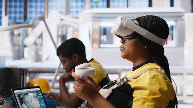 Fotovoltaik fabrikası mühendisi alternatif enerji jeneratörlerinin modellerini yapmak için VR teknolojisini kullanıyor. Güneş panelleri kadın çalışanları sanal gerçeklik teçhizatı kullanarak güvenli güneş hücreleri inşa ediyorlar. Kamera A.