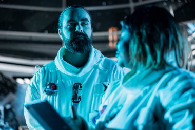 Uzay yolculuğu sırasında güvenli bir operasyon sağlamak için görev parametrelerini tablet üzerinde doğrulayan astronot ekibi. Kozmik yolculuk sırasında uçuş günlüğünü güncelleyen takım çalışması kozmonotları