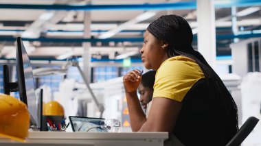 Afrika kökenli Amerikalı mühendis güneş enerjisi fabrikasındaki enerji tüketim yazılımlarını analiz ediyor, güneş pili üretimini arttırmak ve otomatik makine sistemlerindeki hataları azaltmak için PC programını kullanıyor. Kamera A.