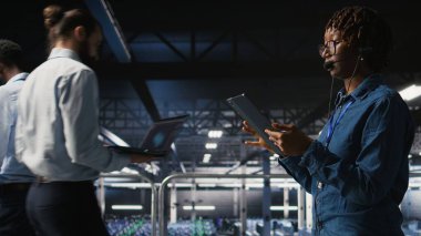 Sunucu odası yönetimi, altyapı teknik desteği sağlamak için tablet ve kulaklık mikrofonu kullanıyor. Veri merkezi bilişim uzmanı uzak ekiplerle koordine ederken arka uç sorunlarını çözer,