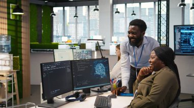 Ofisteki neşeli programcılar, Al ile sürekli tekrarlanan görevleri otomatikleştirerek sohbetin tadını çıkarıyorlar. Mutlu iş arkadaşları sohbet ediyor, yapay zekayı kullanarak uzun metrajlı uygulamaları hızlandırıyor, kamera A