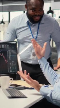 Borsada başarılı ticaret stratejisinden sonra ofisteki dikey videolu Happy çalışanları beşlik çakıyor. PC masasında çalışan neşeli takım çalışanları yatırım kârlarından memnunlar.