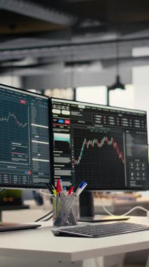 Özel firma ofisinde borsa grafiklerini gösteren dikey video ekranlar. Borsa analizi ve strateji planlaması için kullanılan komisyon işi çalışma masası kurulumu