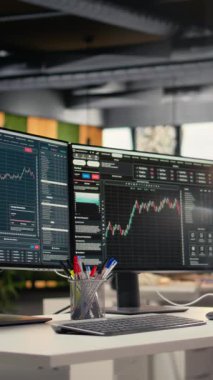 Yatırım fonu ofisindeki bilgisayar ekranlarında görüntülenen dikey video borsa ölçümleri. Finansal yazılım arayüzü önx şirketinin çalışma alanında görünür olan masadaki bilgisayar monitörleri