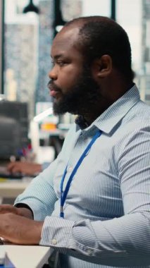 Dikey video Stresli sahne donanımı çalışanı. Platform gösterge panelindeki şüpheli hackleme alarmı yüzünden alarma geçti. Ofisteki Afrikalı Amerikalı adam yazılım ticareti girişimini tespit etti