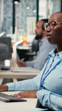 Dikey video günü tüccarı, hisse senedi döviz fiyatları şamdan grafiklerini analiz eder, ofiste alım satım kararları verir. Afrikalı Amerikalı kadın müşteri siparişlerini ticaret platformu B 'ye yerleştiriyor.