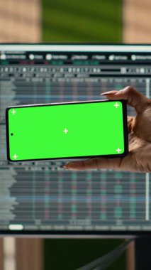 Portföy yöneticisinin eğitim içeriğini izlemek için akıllı telefonu kullanarak portföy yöneticisinin dikey görüntüsü. Yönetimdeki serbest fon uzmanı yeşil üzerine video dersinden yeni ticaret stratejileri öğreniyor