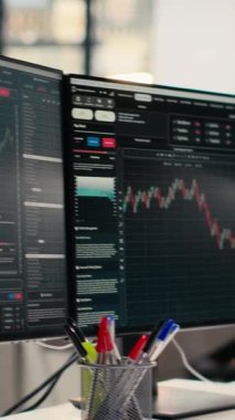 Yatırım fonu ofisindeki bilgisayar ekranlarında görüntülenen dikey video borsa ölçümleri. Finansal yazılım arayüzü önx şirketinin çalışma alanında görünür olan masadaki bilgisayar monitörleri