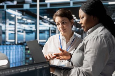 Veri merkezindeki sistem yöneticilerinden oluşan bir ekip, depolama dizilerini güncellemek için dizüstü bilgisayar kullanarak ağ viralizasyonunu yapılandırıyor. Ayarları doğrulamak için dizüstü bilgisayar kullanan sunucu merkezi bilişim uzmanları