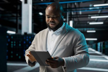 Sunucu çiftliğinde mühendis yedek protokolleri koordine ediyor, kurtarma planlarını kontrol ediyor. Veri merkezi bilişim uzmanı tabletle bakım yapıyor, platformların optimum olarak çalıştığından emin oluyor.