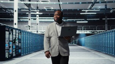 Gülümseyen sunucu odası mühendisi dizüstü bilgisayardaki yazılımı kullanarak sunucu raflarında bakım yapıyor. Happy Veri Merkezi IT profesyonel bıçak sunucu bileşenlerini not defteri, kamera A kullanarak güncelliyor