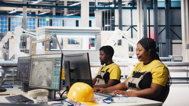 Fotovoltaik tesisteki yardım masasında çalışan siyah mühendis, kulaklıkla çağrılara cevap veriyor, teknik sorunları çözmede yardım ve destek öneriyor. Kadın operatör yardım hattında. Kamera B.