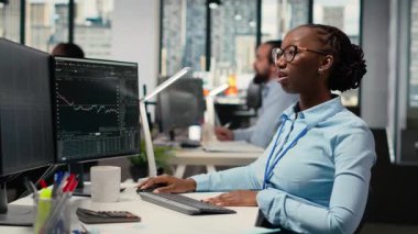 Borsa simsarları, borsa fiyatlarını, şamdan grafiklerini analiz eder, ofiste alım satım kararları verir. Afrikalı Amerikalı kadın müşteri siparişlerini ticaret platformu B 'ye yerleştiriyor.