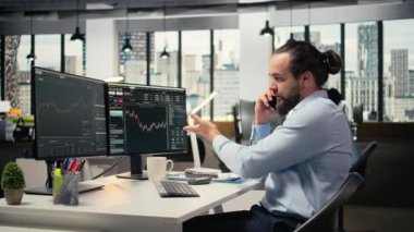 Yatırım danışmanı müşteriyle telefonda konuşuyor, portföy performansını gözden geçiriyor. Tüccar müşteriyle telefon görüşmesi yapmak için akıllı telefon kullanıyor, finansal strateji sağlıyor, kamera A