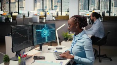 Ofisteki tüccar, analitik çizelgeleri yorumlamak, alım ve satımı optimize etmek için yapay zeka teknolojisini bilgisayar üzerinde kullanıyor. Afrikalı Amerikalı kadın kazancı maksimuma çıkarmak için derin öğrenme otomatikleştirmesi kullanıyor. Kamera A.