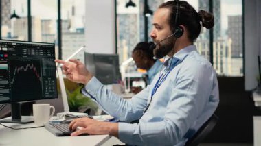 Yatırım danışmanı mikrofonla konuşuyor, müşteri portföy performansını gözden geçiriyor. Tüccar müşteriyle tartışıyor, mali büyüme tahmin ediyor ve özel strateji sağlıyor, kamera B