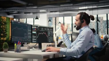 Yatırım danışmanı mikrofonla konuşuyor, müşteri portföy performansını gözden geçiriyor. Tüccar müşteriyle tartışıyor, finansal büyümeyi tahmin ediyor ve özel strateji sağlıyor, kamera A