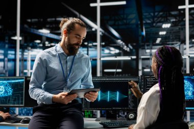 Veri Merkezi yöneticisi ve stajyer yapay zeka model parametrelerini güncelliyor. Sunucu odası bilişim takımı lideri ve stajyer programlama makinesi öğrenimi donanım bileşenleri için bakım işletiyordu