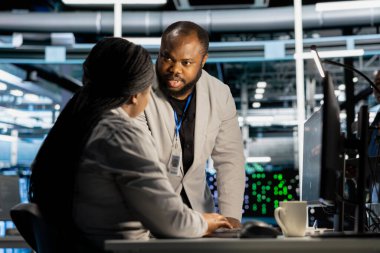 Veri Merkezi Mühendislik Ekibi bilgisayarda tanısal betikler çalıştırıyor, donanımı inceliyor. Sunucu odası takım arkadaşı performans ölçümlerini değerlendirmek için bilgisayar kullanarak sistem istikrarını koruyor