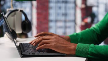 Freelancer, internet günlüğü için yazı içeriği hazırlıyor, dizüstü bilgisayarıyla hikaye anlatma üzerine çalışıyor. Siyahi adam sosyal medya paylaşımları yazıyor, birden fazla iş yapıyor. Kamera A.