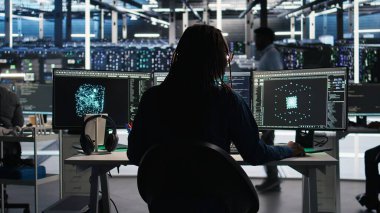 Yapay zeka analizi grafiklerini yorumlayan sunucu odası programcısı, kulaklık takıyor. Veri merkezi bilişim uzmanı sistem ölçümlerini, dinleme müziğini ve kamera A 'yı gösteren yapay zeka aracı kullanıyor.